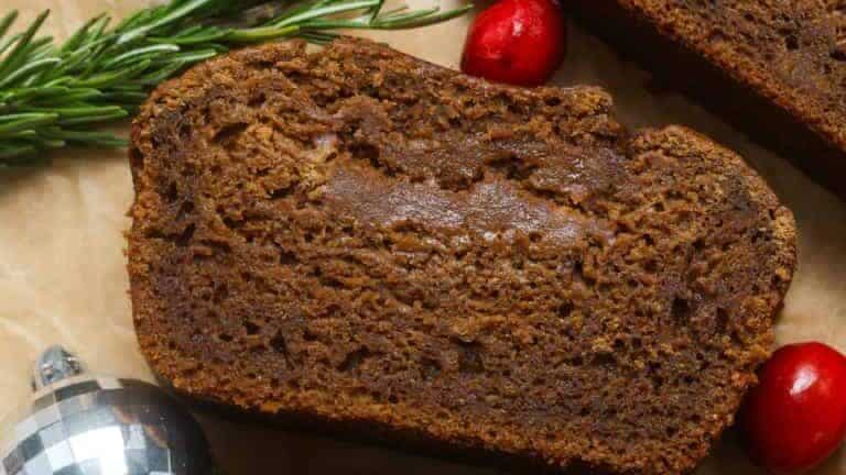 A slice of gingerbread with cranberries and sprigs of holly.