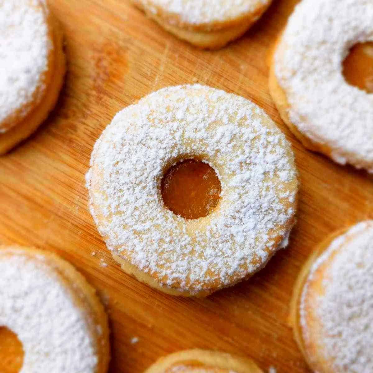 Unique Cookie Recipes: Donuts with powdered sugar on a wooden cutting board.