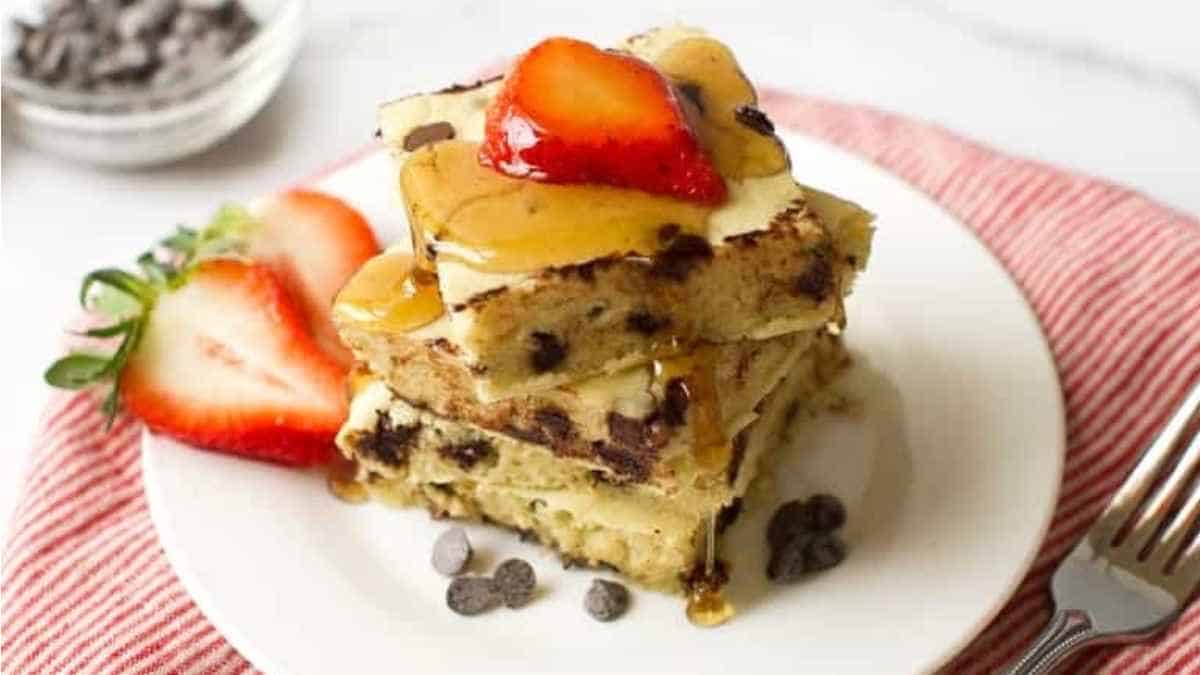 A stack of chocolate chip banana bread with strawberries on a plate.