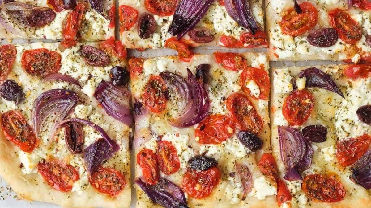 A pizza with tomatoes, onions and feta cheese.