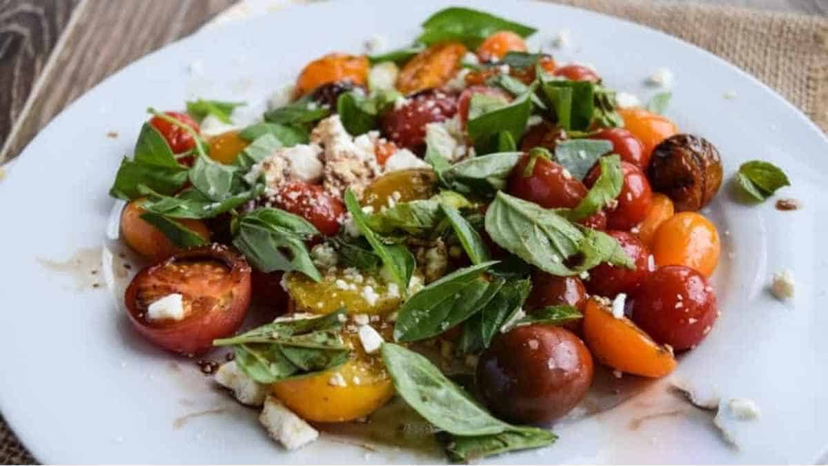 A plate with tomatoes, basil and feta cheese.