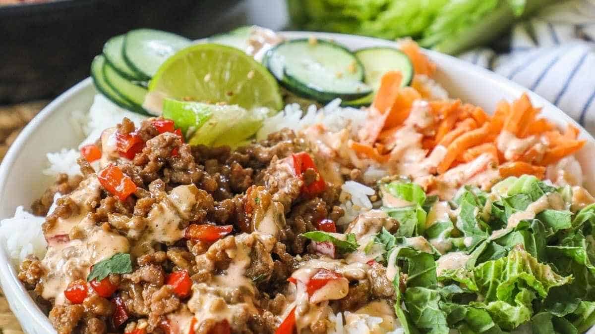 A bowl of thai beef salad with lettuce, carrots and cucumbers.