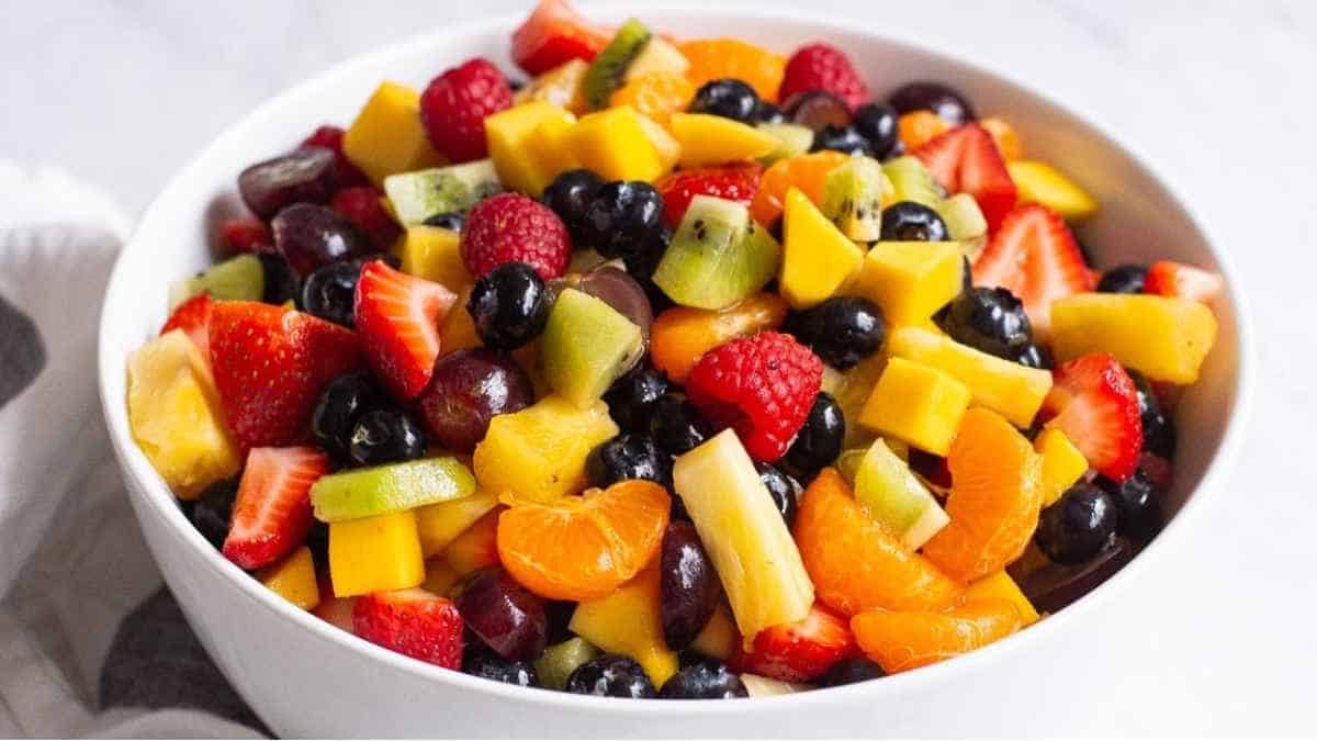 A bowl of fruit salad in a white bowl.