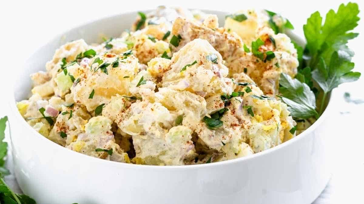 Potato salad in a white bowl with parsley.