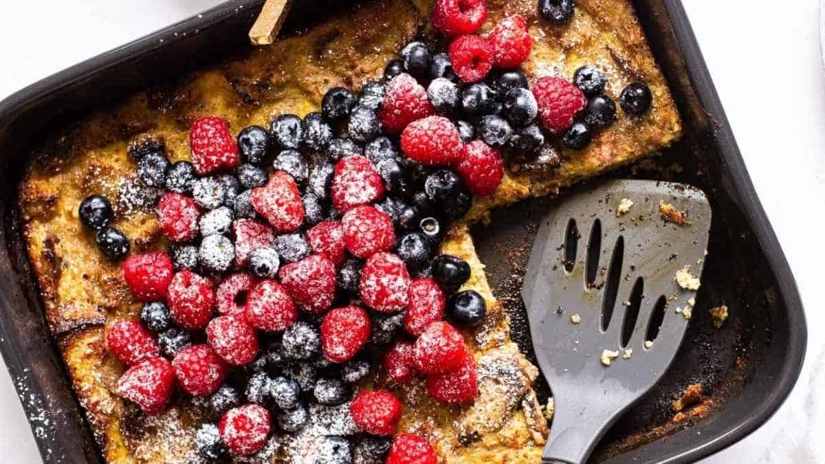 A black pan with berries and a spatula.