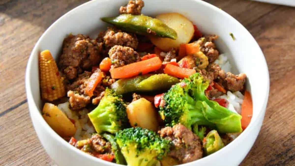 A bowl of stir fry with meat, vegetables and rice.
