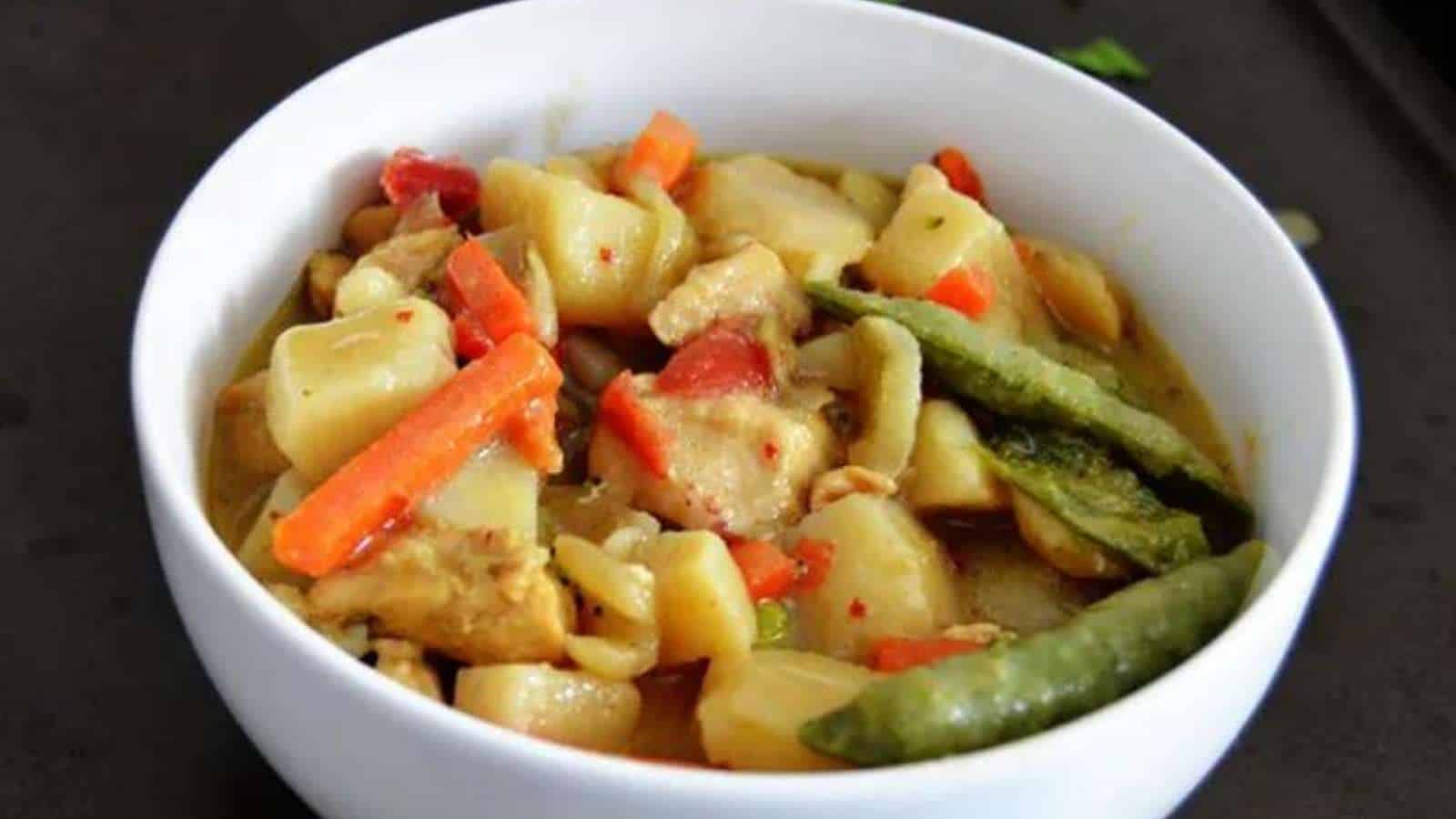 A bowl of chicken curry with vegetables and noodles.