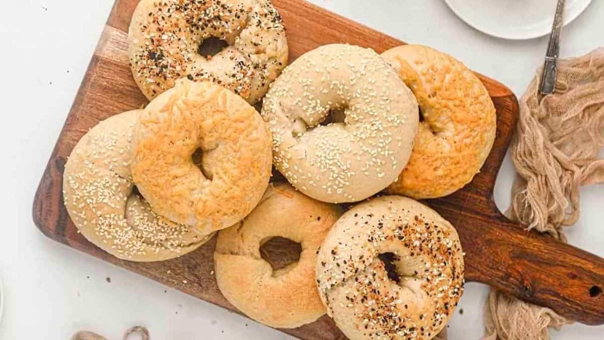 Bagels with sesame seeds on a wooden cutting board.