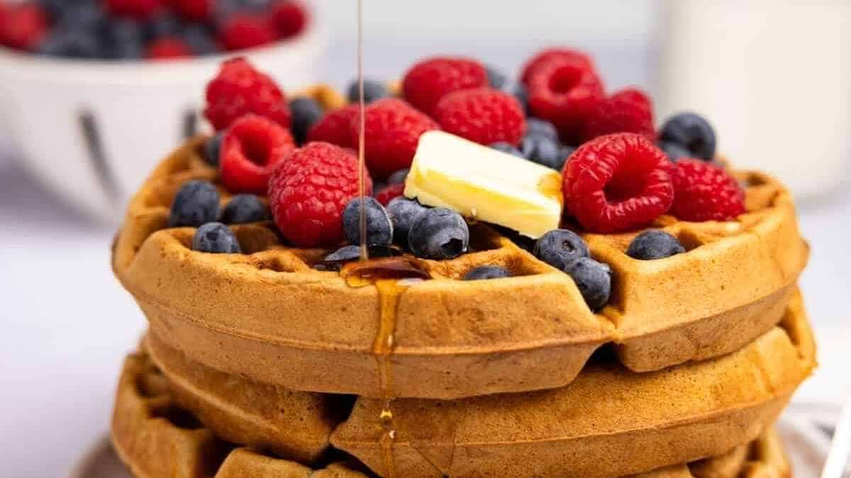 A stack of waffles with berries and syrup.