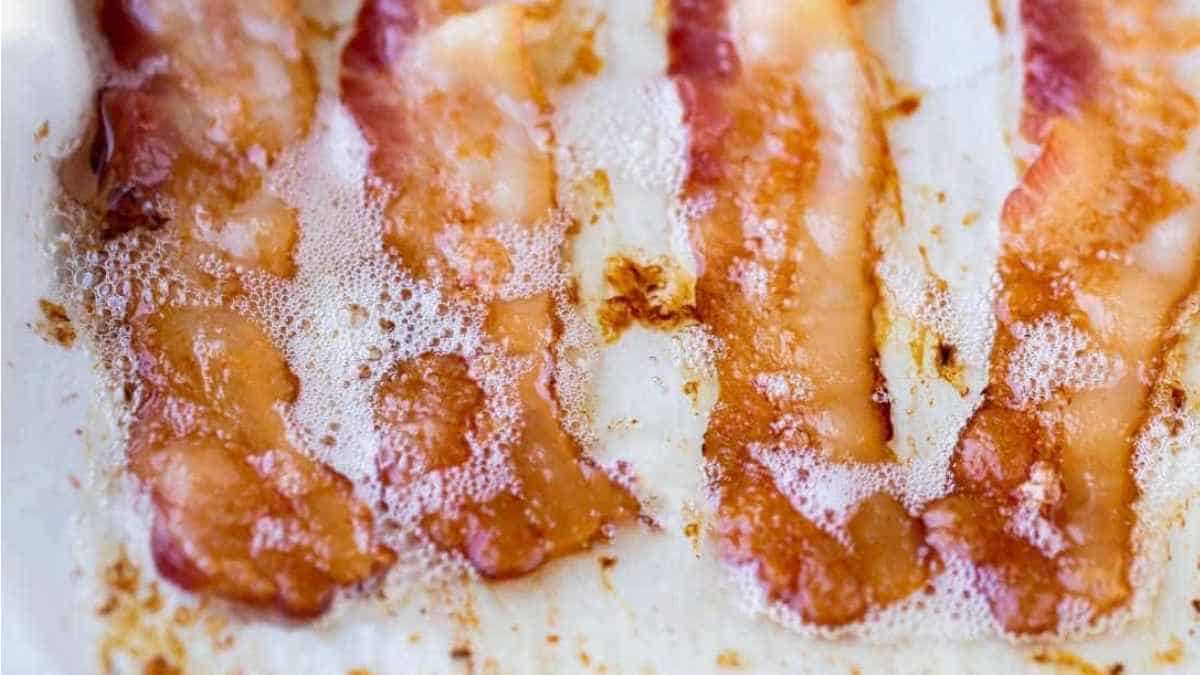 Bacon on a baking sheet with a spatula.