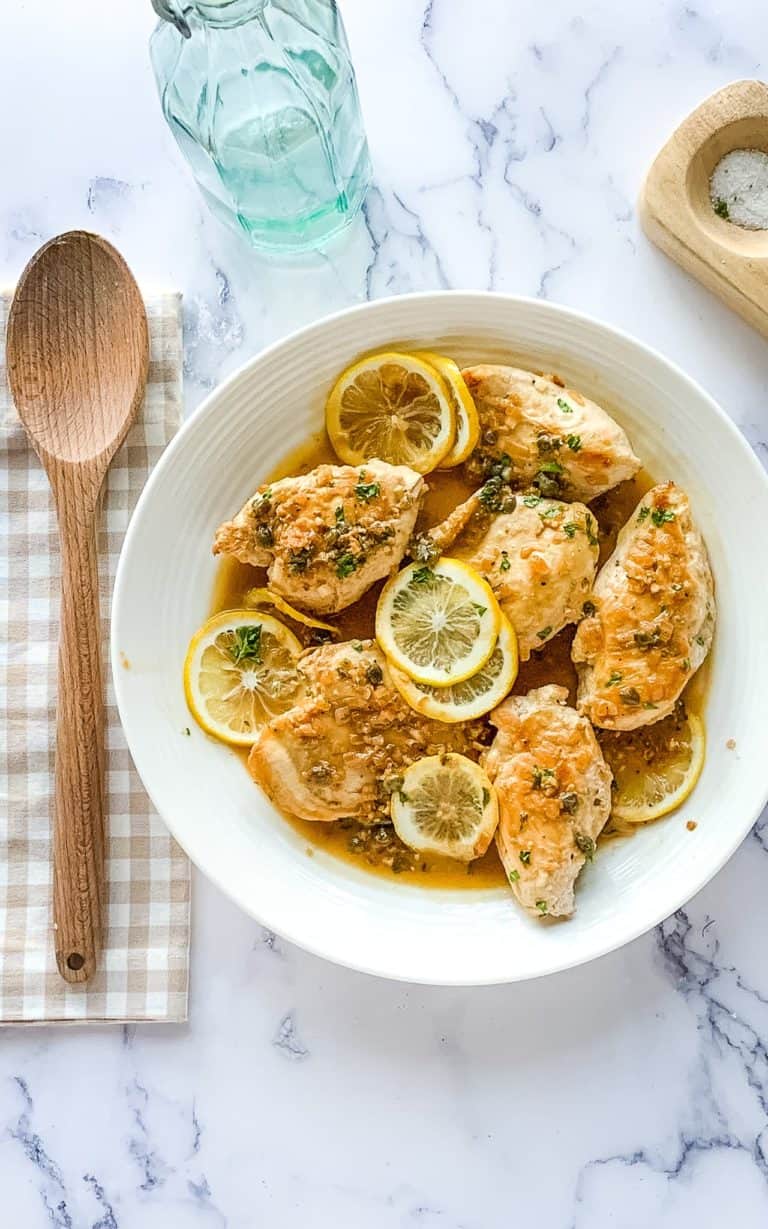 Lemon caper chicken cutlets on a white serving platter.
