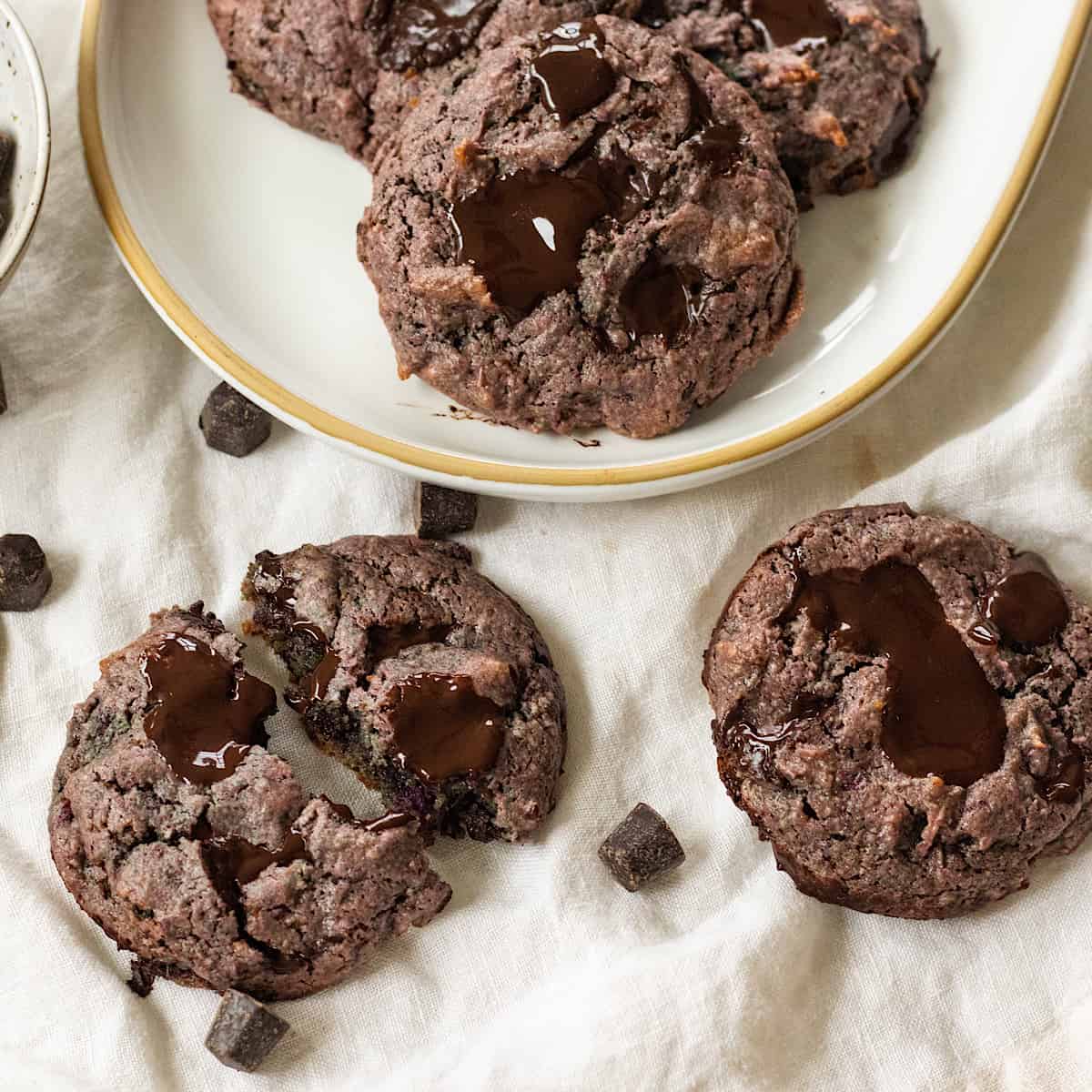 Unique chocolate chip cookies on a plate with a bite taken out.