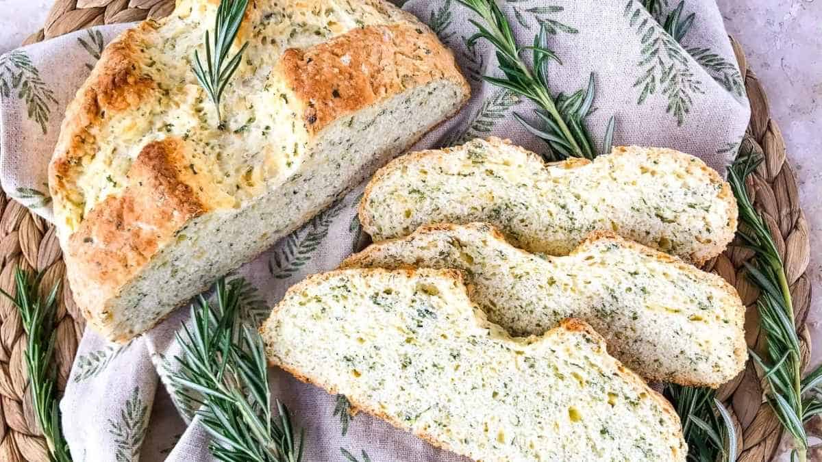 A loaf of rosemary bread with rosemary sprigs on a wicker basket.