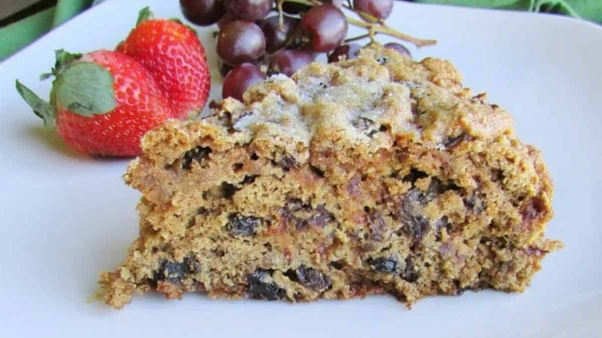 A piece of cake with strawberries and grapes on a plate.