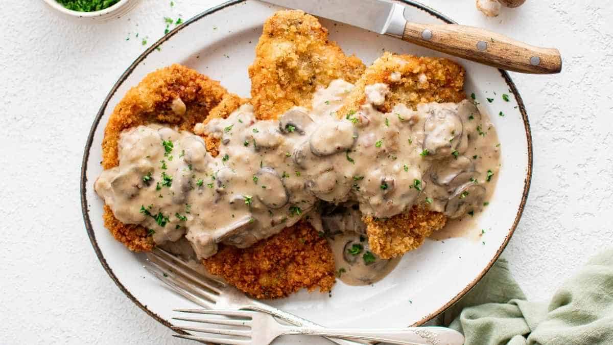 A plate of fried chicken with mushroom sauce.