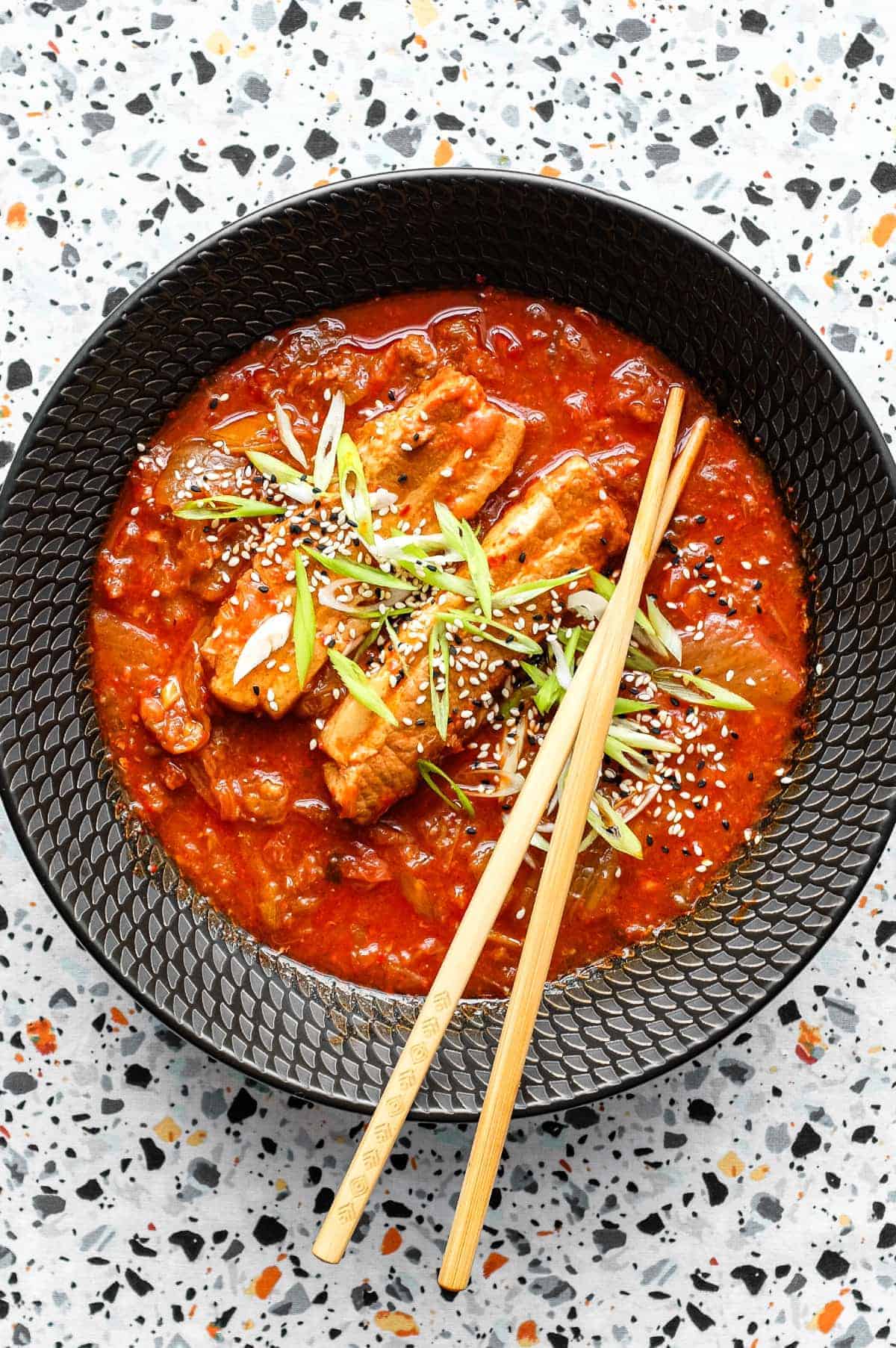 A tantalizing bowl of stew featuring succulent pork belly, enjoyed with chopsticks.
