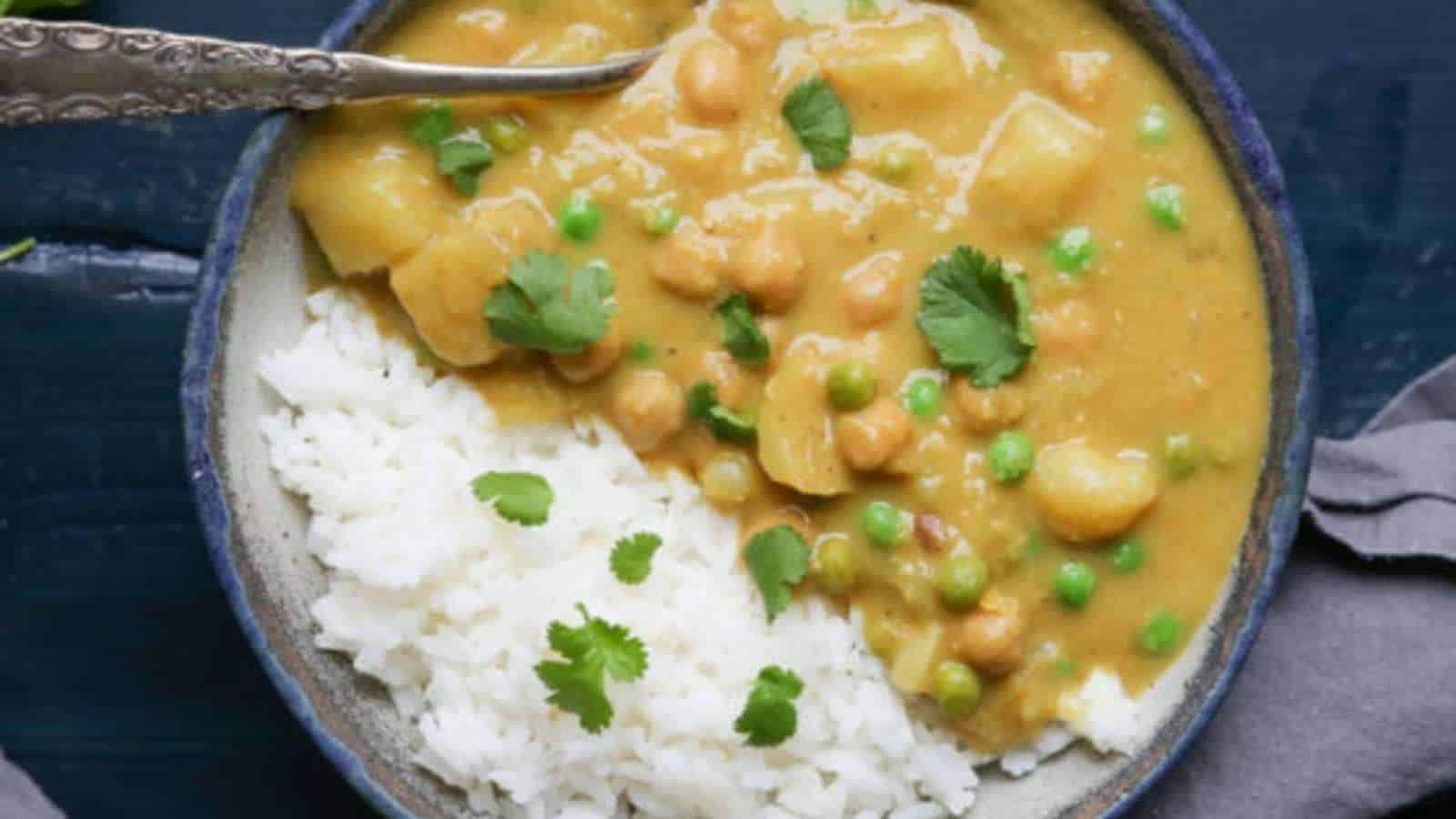 A bowl of curry with rice and peas.