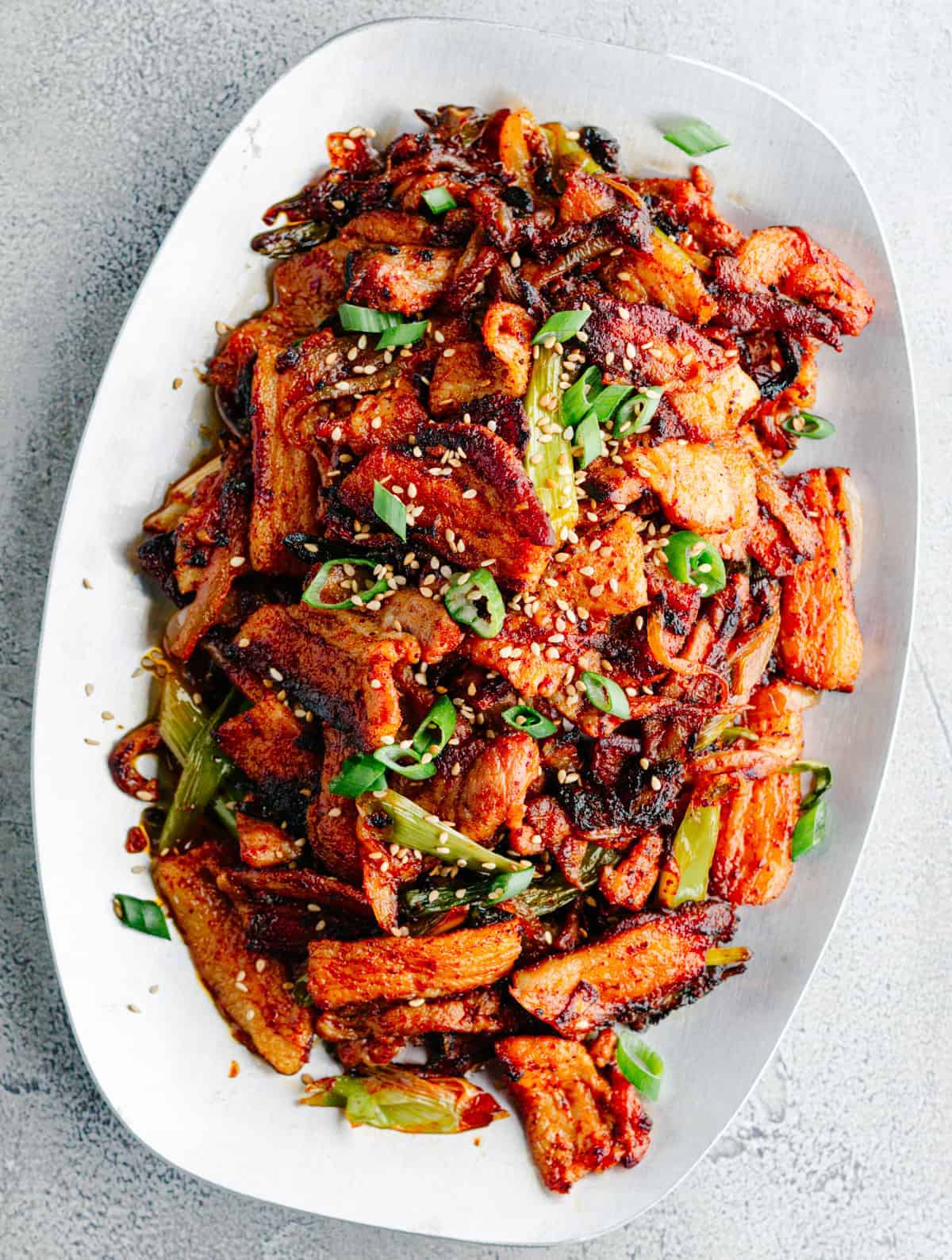 Korean fried tofu with pork belly on a white plate.