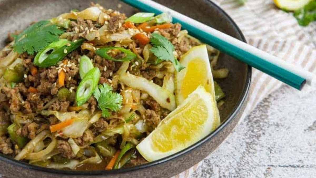 A bowl of stir fried noodles with meat and vegetables.