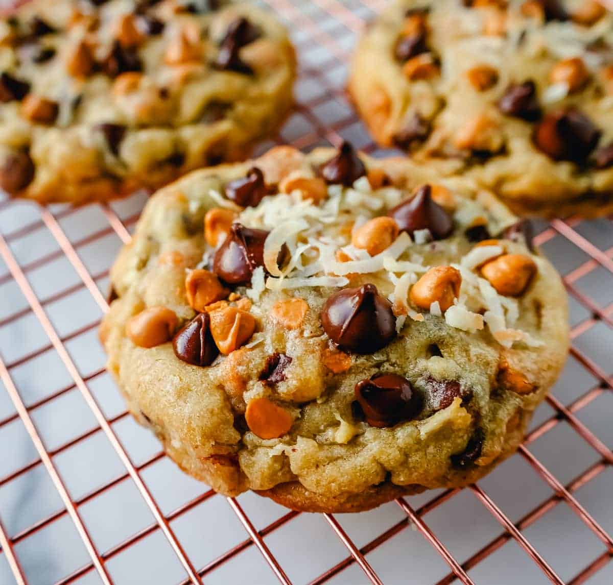 Three unique chocolate chip cookie recipes cooling on a rack.