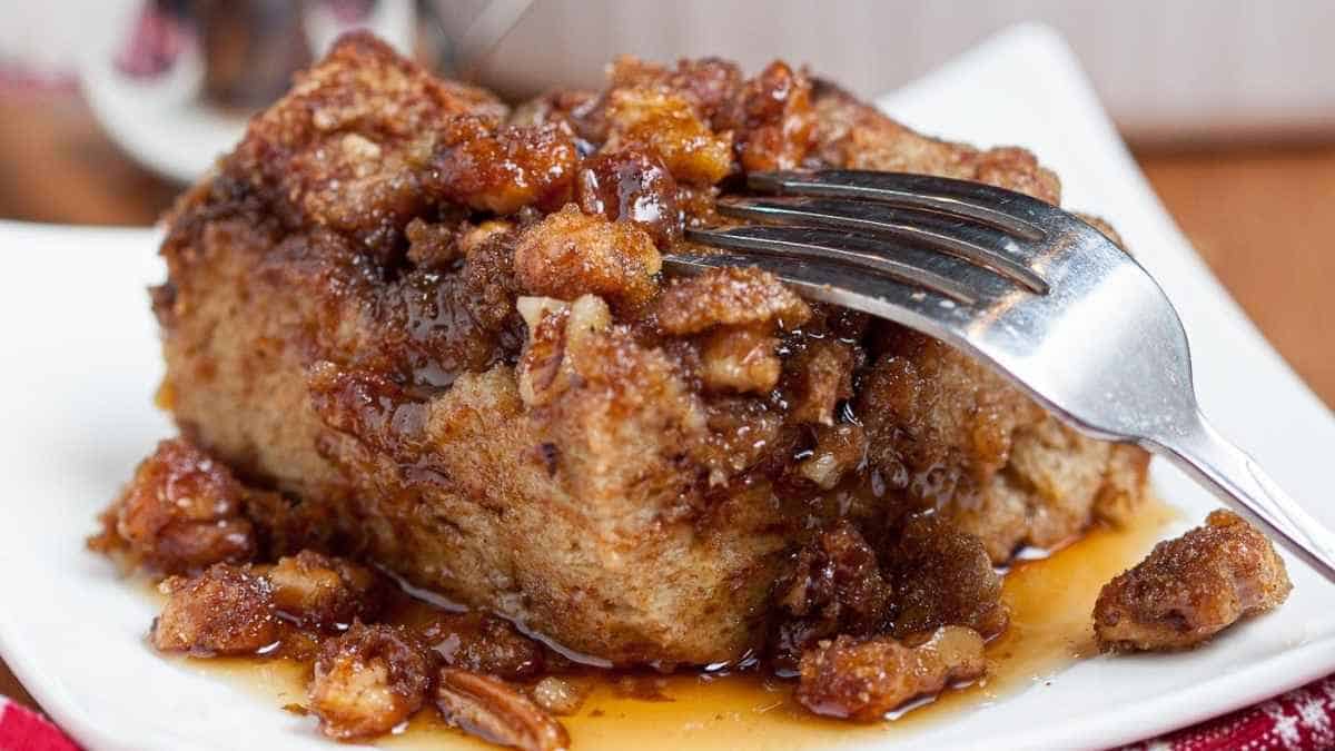 A piece of bread pudding with a fork on a plate.