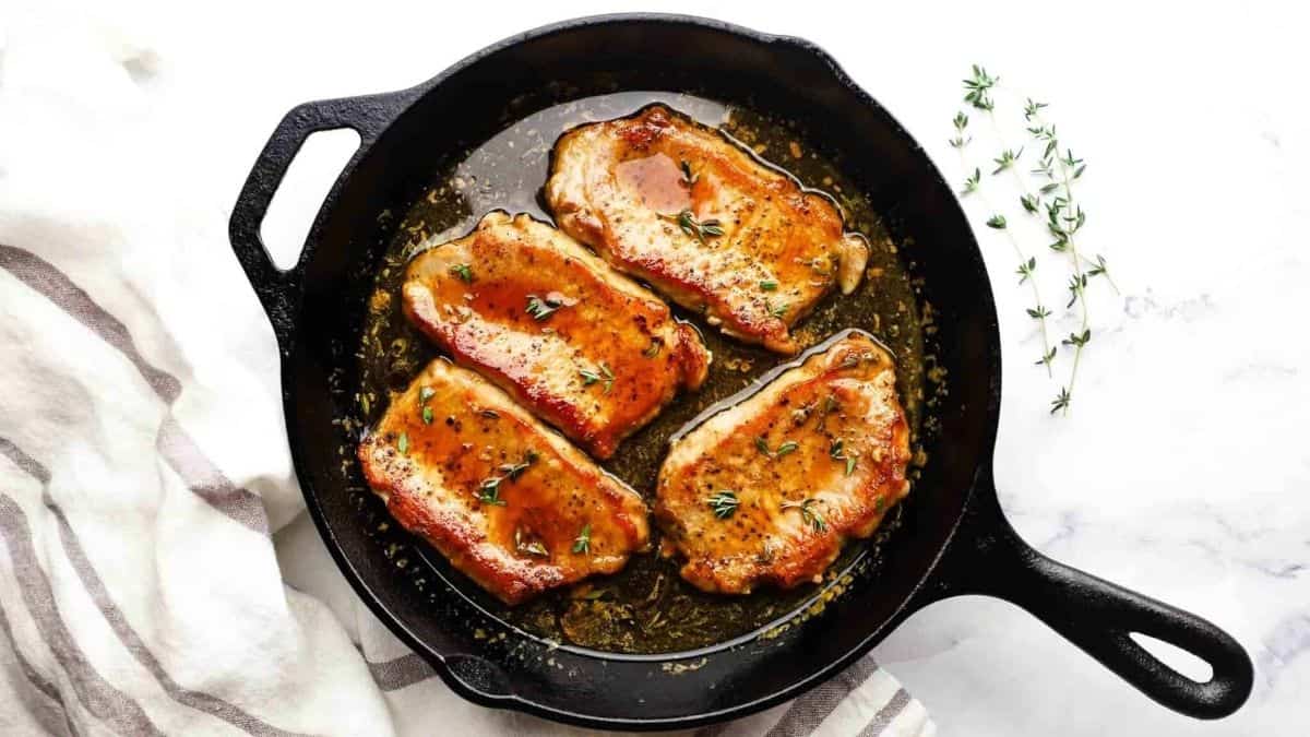 Pork chops in a cast iron skillet with herbs.