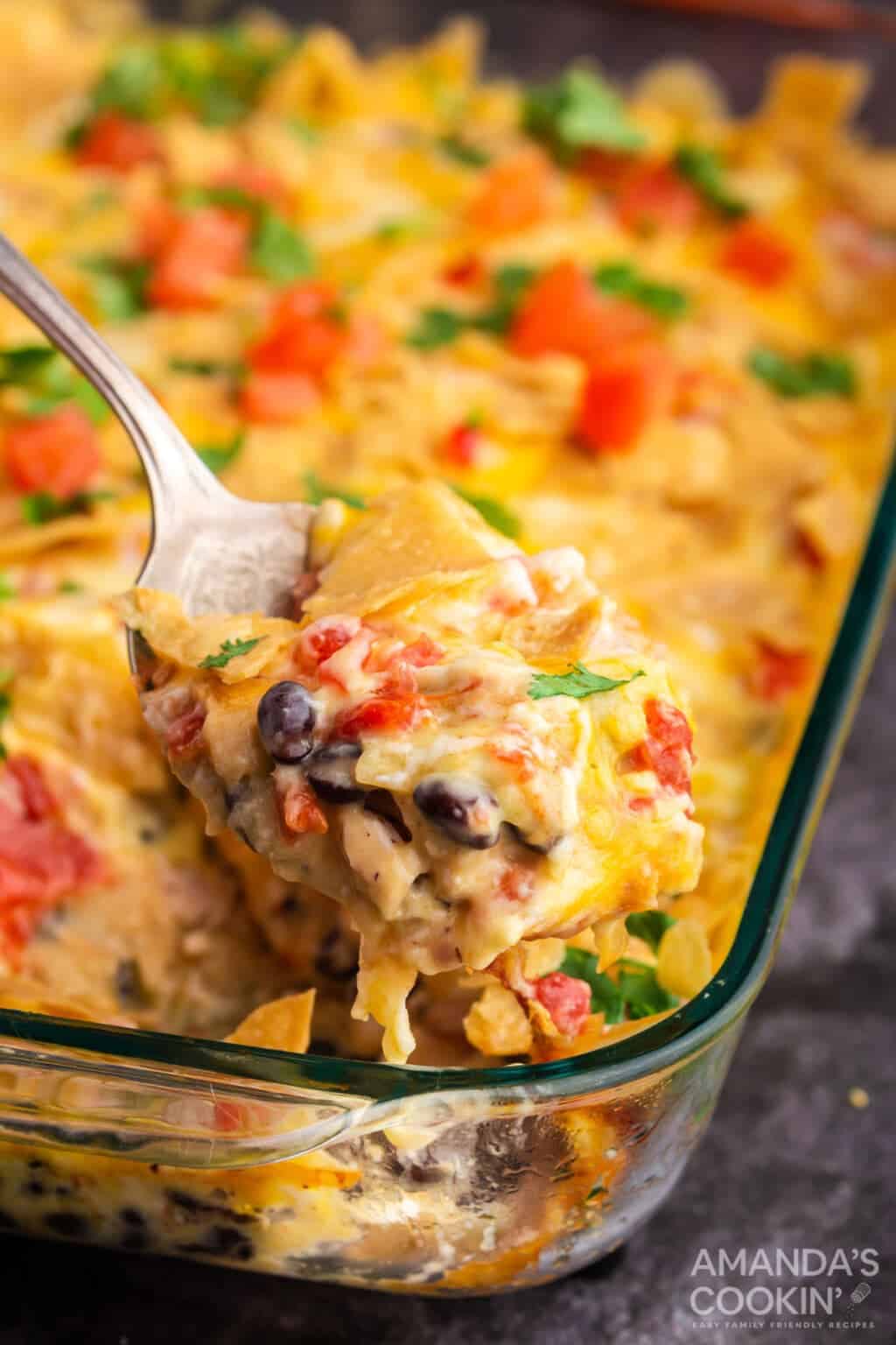 spoon lifting out a serving of mexican chicken casserole / Only 10 ingredients and 30 minutes in the oven, and you're family will be enjoying this delicious Mexican Chicken Casserole!
