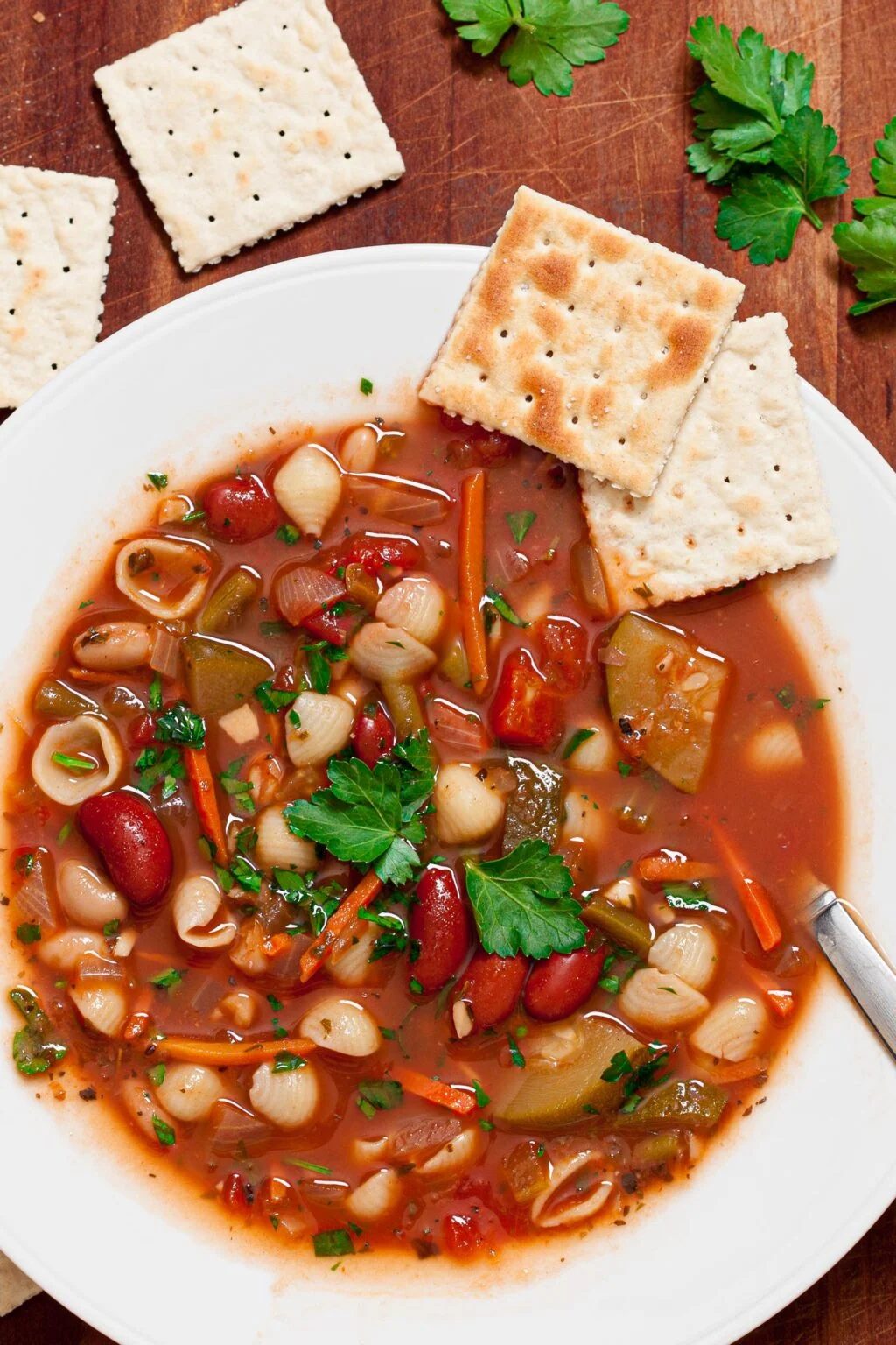 Minestrone Soup in a white bowl with crackers.
