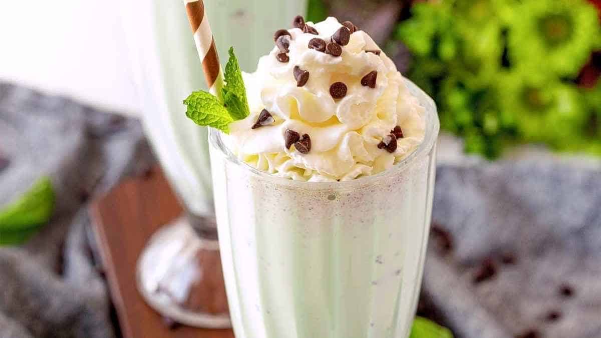 Mint chocolate chip milkshake with whipped cream and mint leaves.