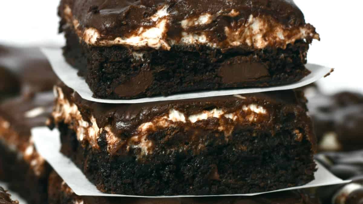 A stack of brownies with chocolate frosting.
