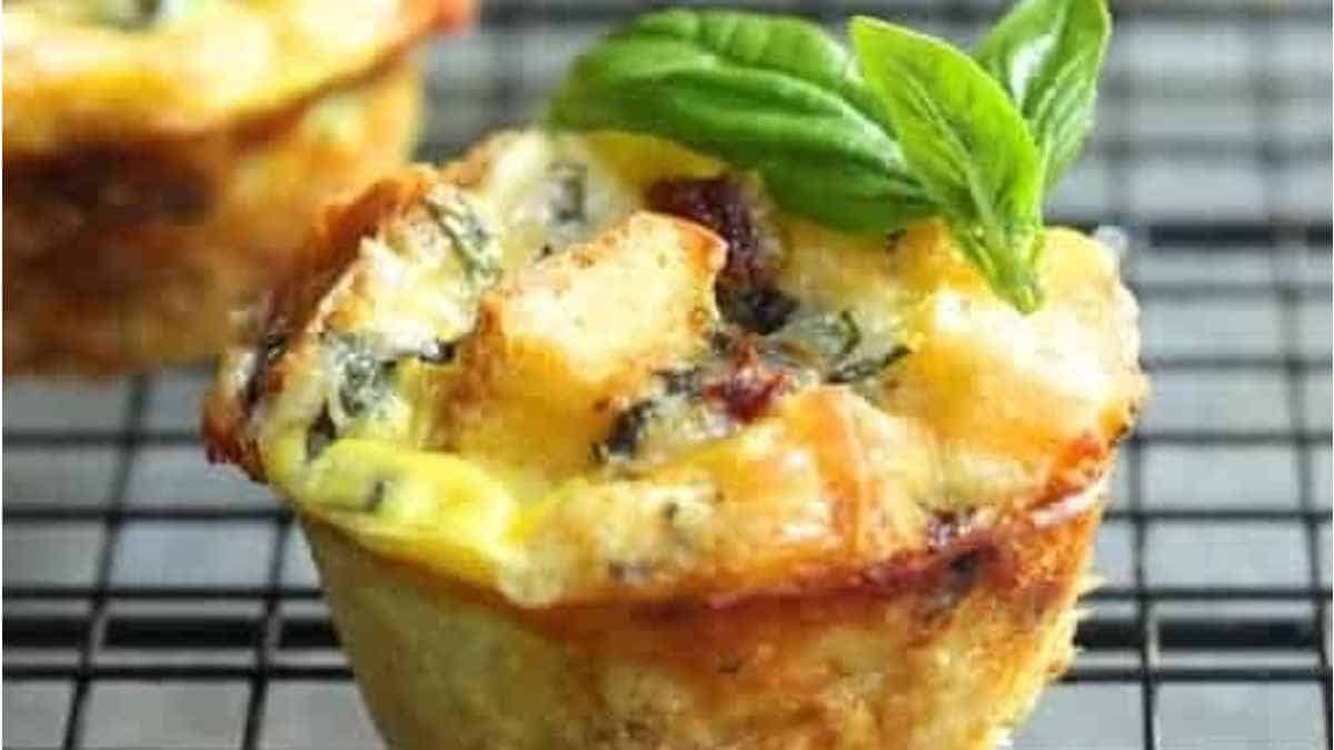 Breakfast muffins on a cooling rack with basil leaves.