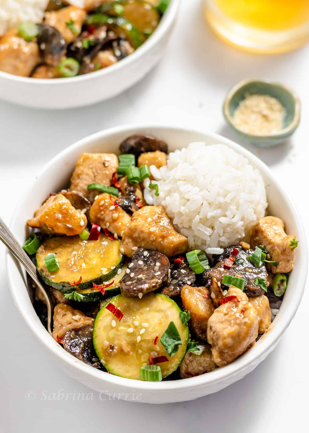 A bowl of chicken stir fry with vegetables and rice.