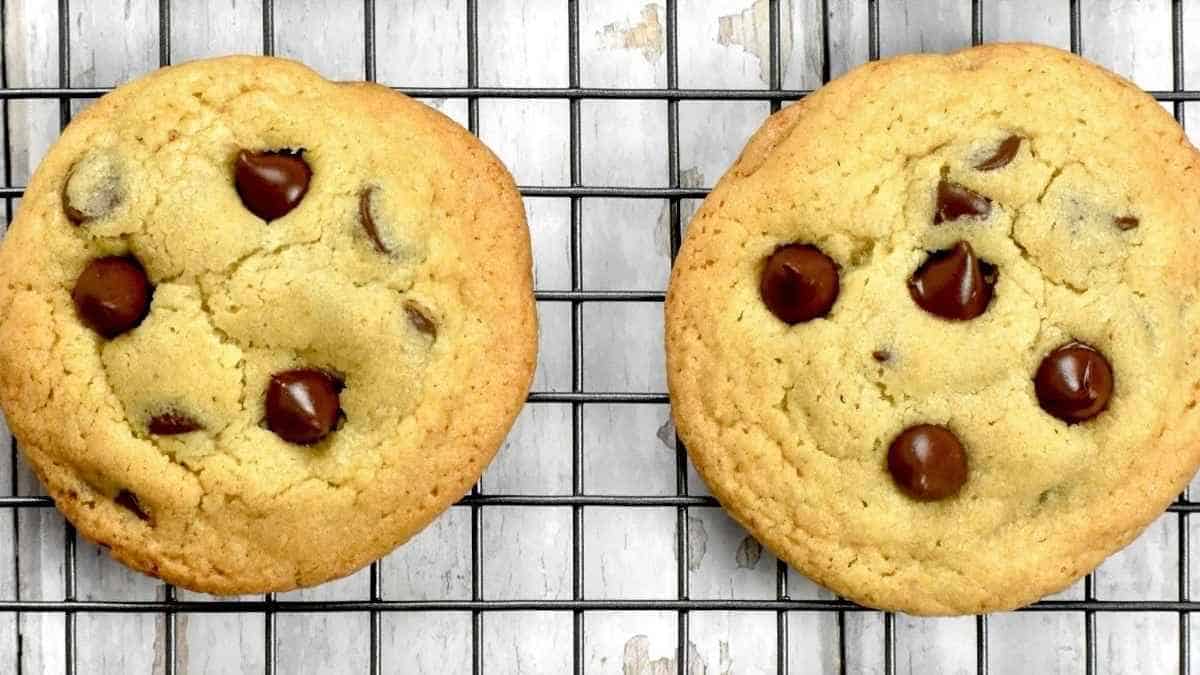 Two chocolate chip cookies on a cooling rack.