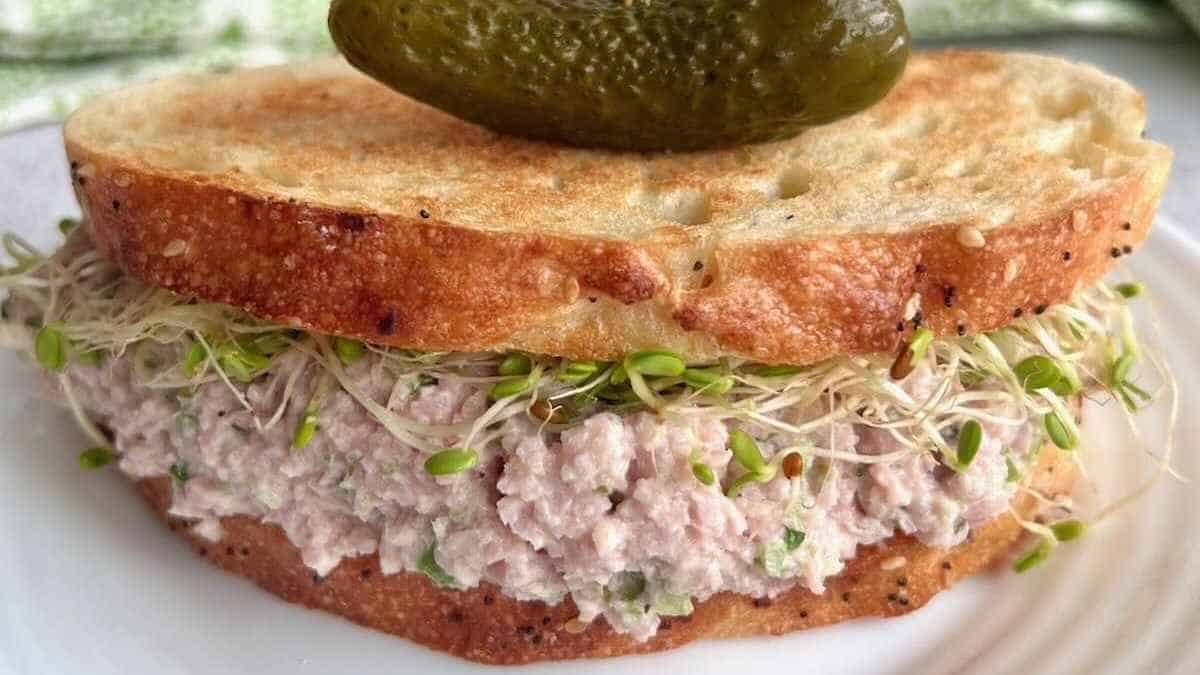 A sandwich with tuna and sprouts on a plate.