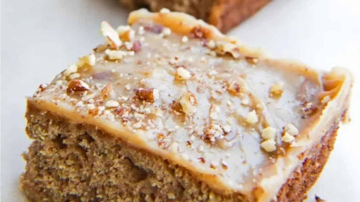 A piece of cake with caramel and pecans on top.