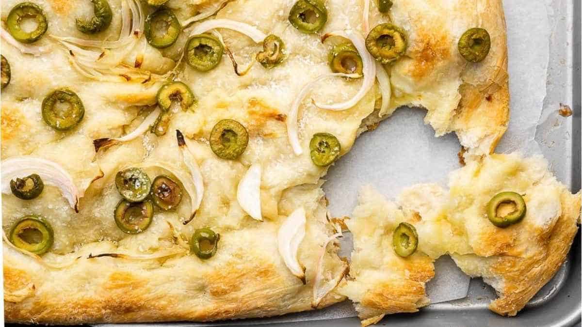یک تکه پیتزا با هالاپنو و پیاز روی یک ورقه پخت.