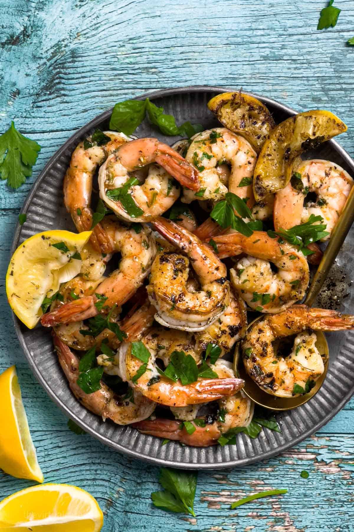 Grilled shrimp with lemon and parsley on a plate.