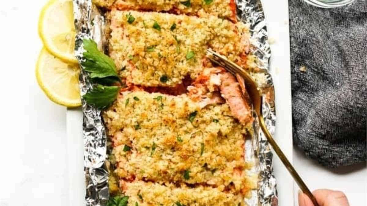 Salmon baked in foil with lemon wedges.