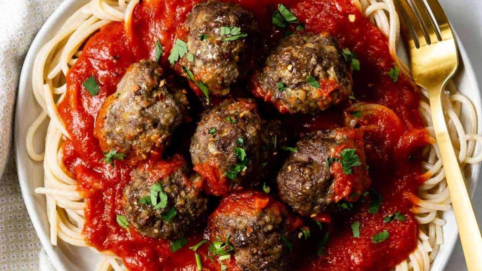 Meatballs on a plate with spaghetti and sauce.