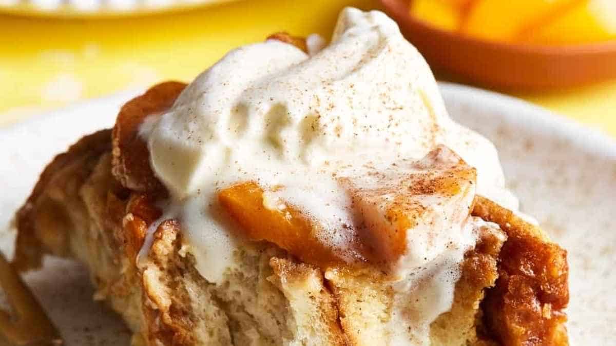 A slice of bread pudding topped with whipped cream and peaches.