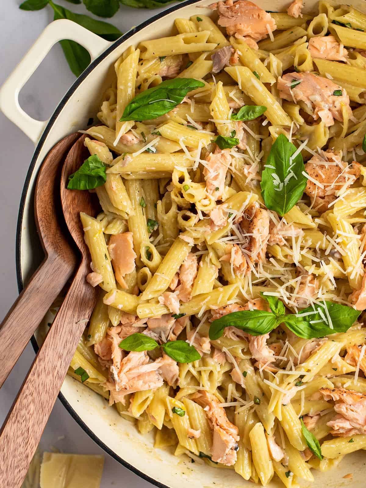 penne al salmone in a white dutch oven with serving spoons.
