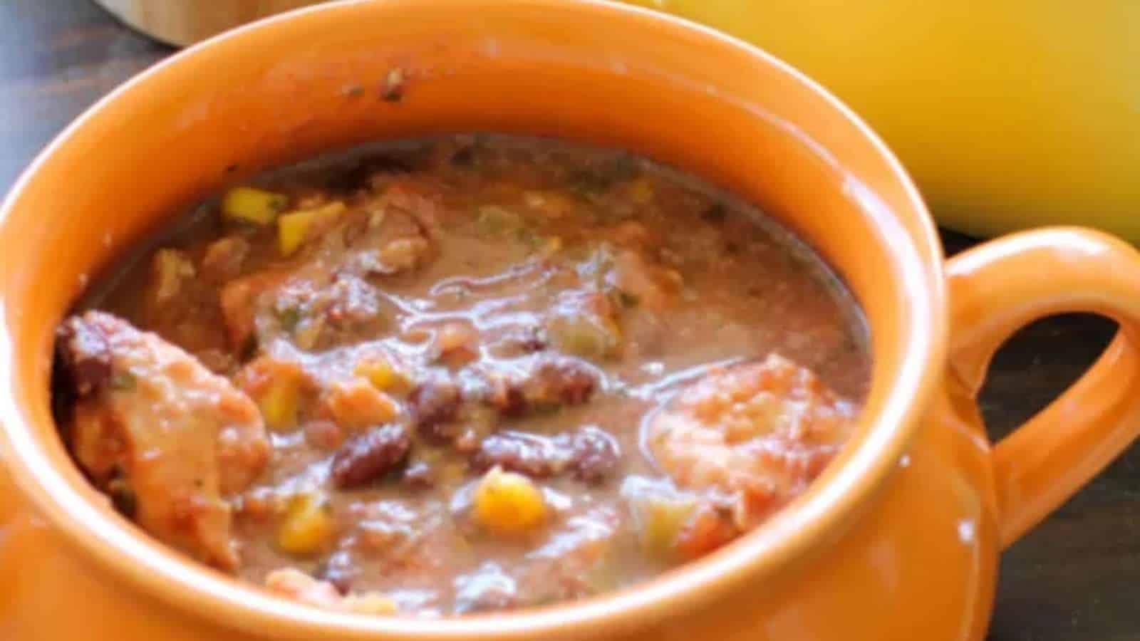 A bowl of chili with beans and corn on a table.