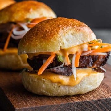 Asian pork sliders on a wooden cutting board, perfect for those searching for delicious pork belly recipes.