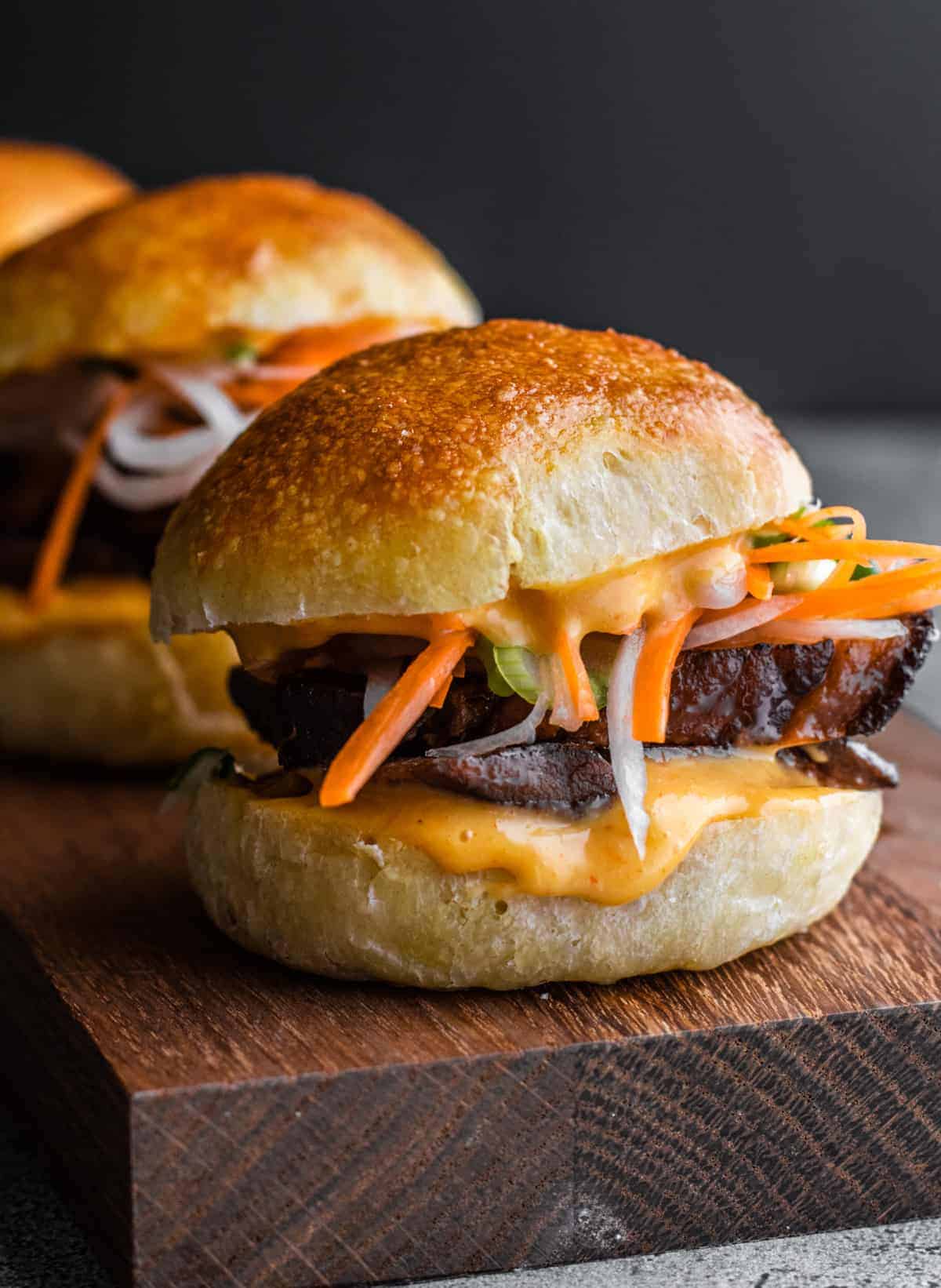 Asian pork sliders on a wooden cutting board, perfect for those searching for delicious pork belly recipes.