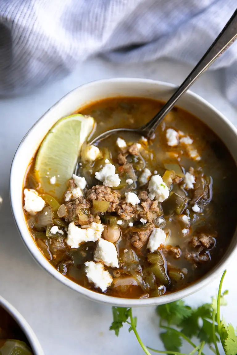 A bowl of mexican soup with meat and cheese.