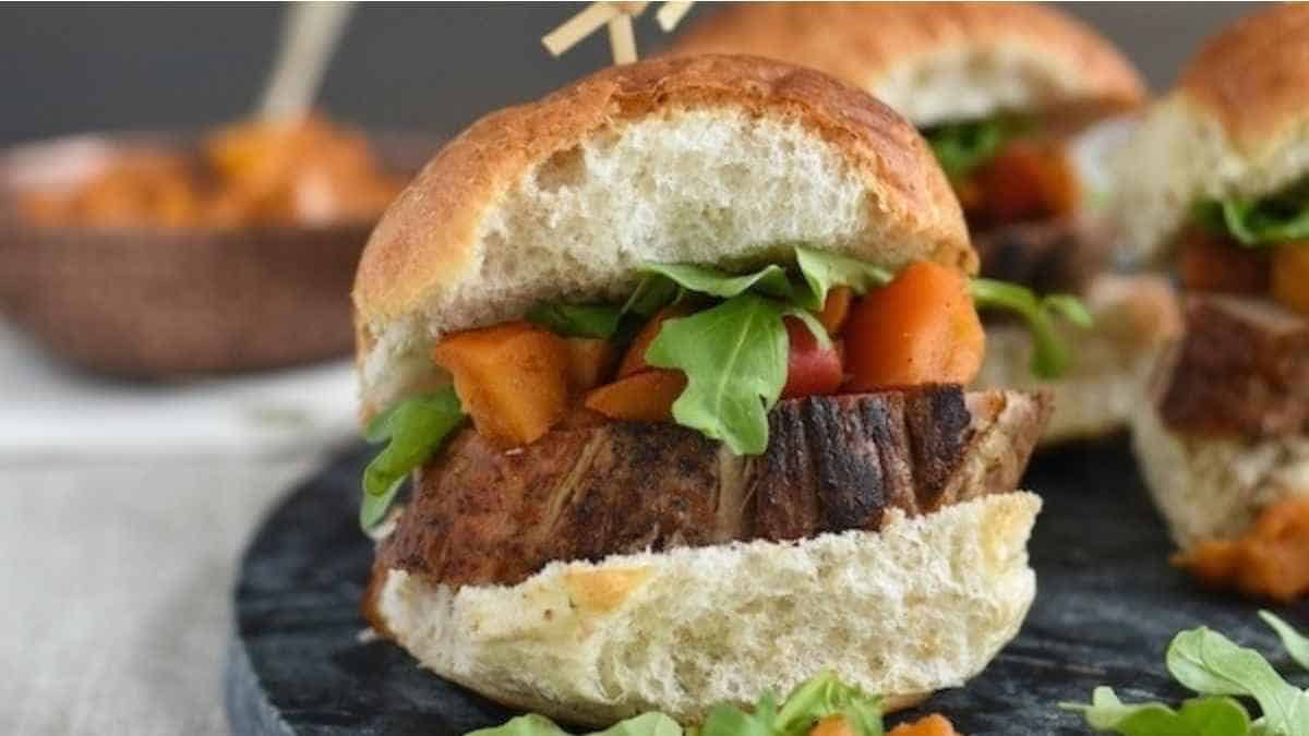 A plate of sliders with meat and vegetables on it.
