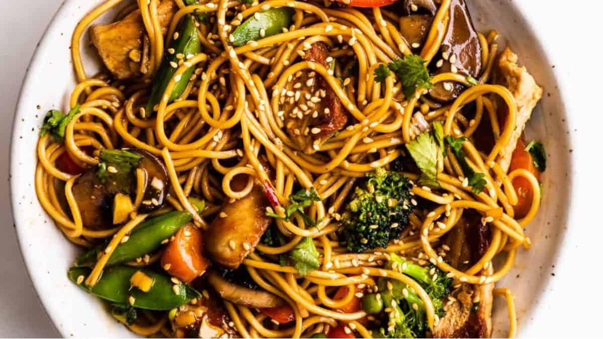 A bowl of stir fried noodles with vegetables and mushrooms.