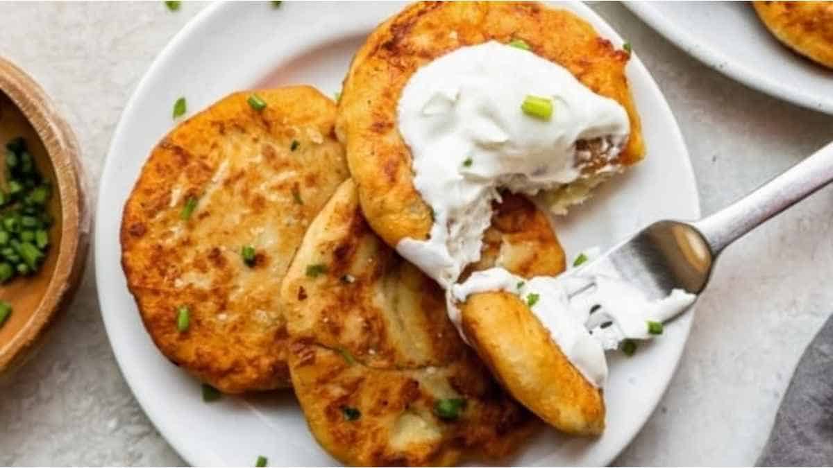 A plate of pancakes with sour cream and peas.