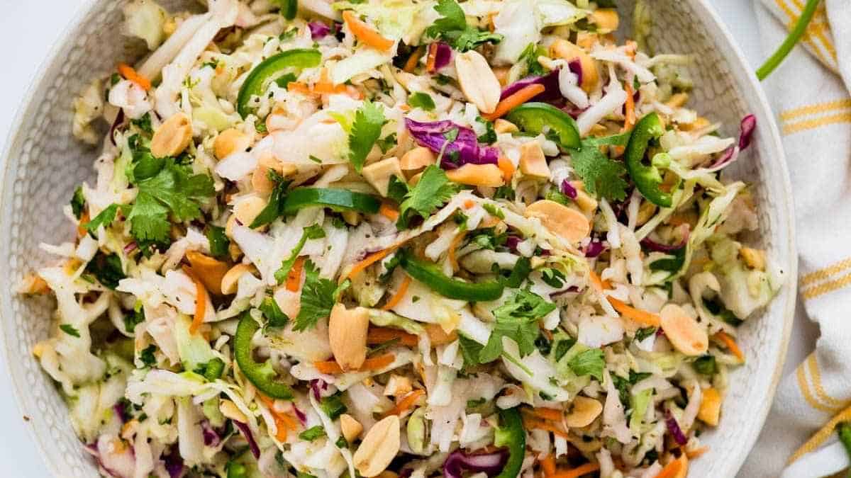A bowl of asian slaw with peanuts and carrots.