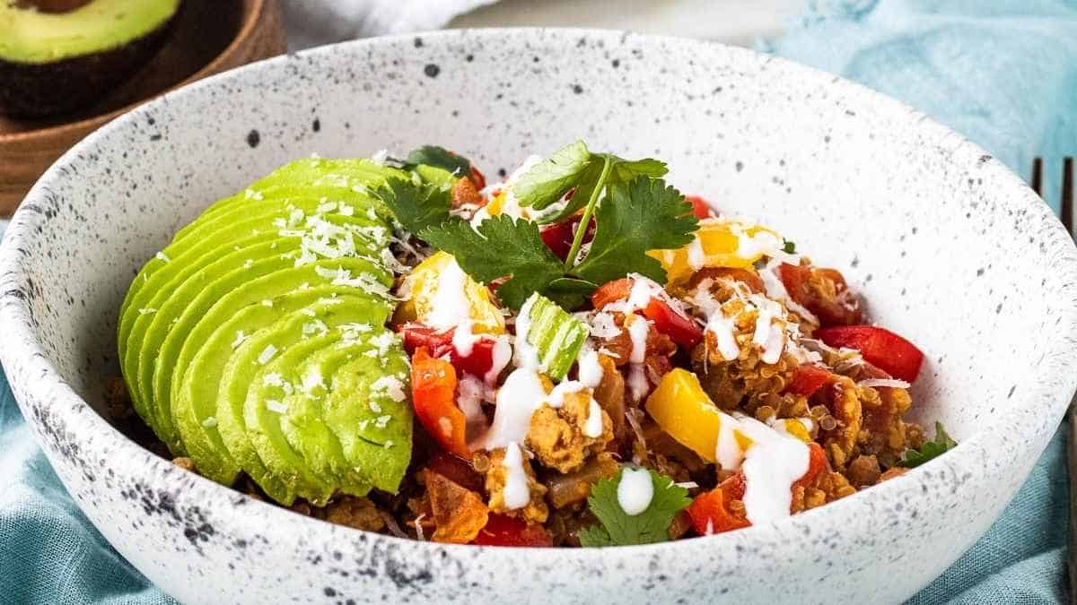 A bowl filled with chicken, avocado and tomatoes.